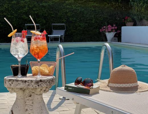 Relax estivo a bordo piscina con cocktail e sole.